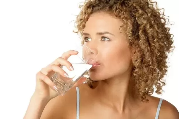 The girl follows a diet for the lazy and drinks a glass of water before eating